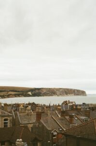Coastal town with rooftops overlooking the sea and cliffs.